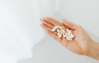 A close-up shot of a hand holding loose human teeth on a white background.