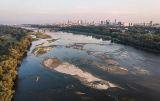 Stunning aerial view of Wisla River meandering through Warsaw's skyline at sunset.