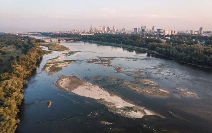 Stunning aerial view of Wisla River meandering through Warsaw's skyline at sunset.